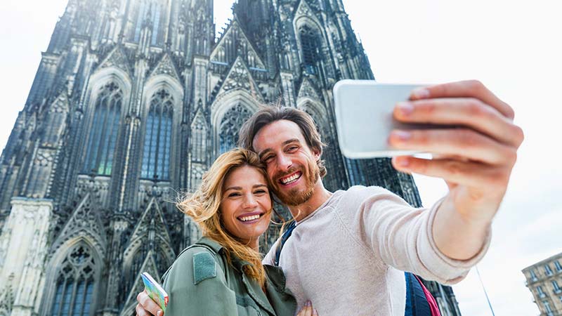 A young couple take a selfie in front of the Cologne Cathedral in Germany.