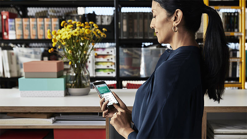 woman in a shop paying on her phone near the counter